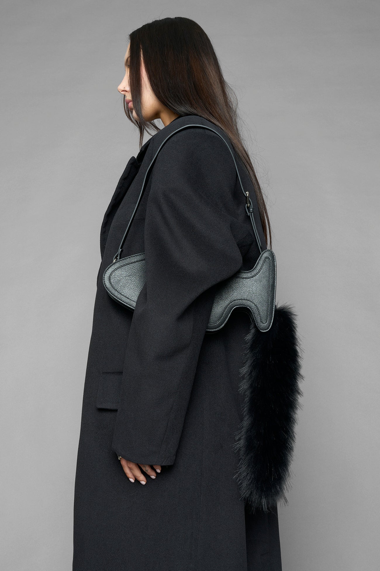 black butt plug bag with adjustable strap and faux fur detail worn as shoulder bag studio ecommerce image