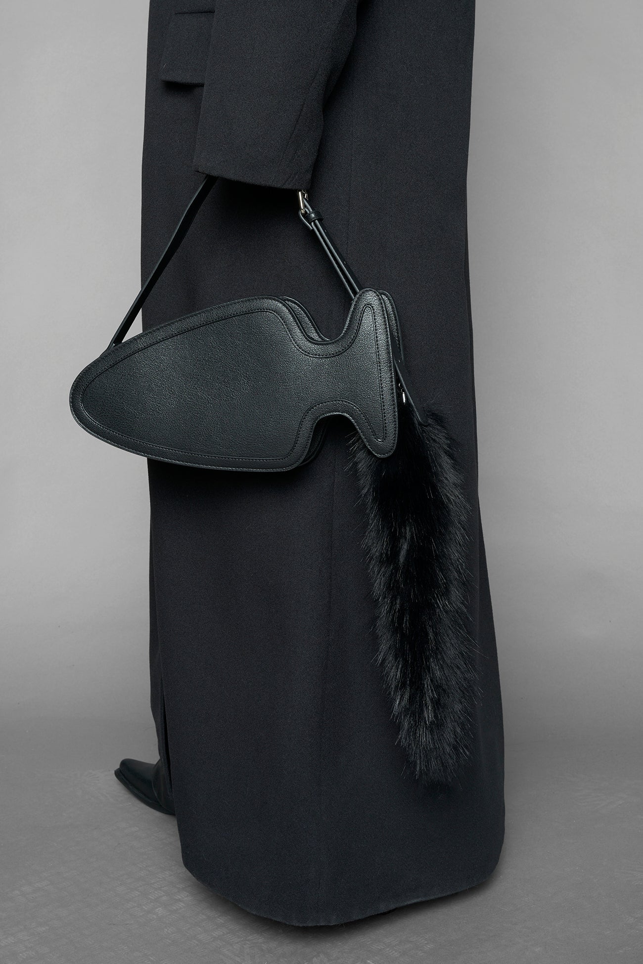 black butt plug bag with adjustable strap and faux fur detail worn as shoulder bag studio ecommerce image