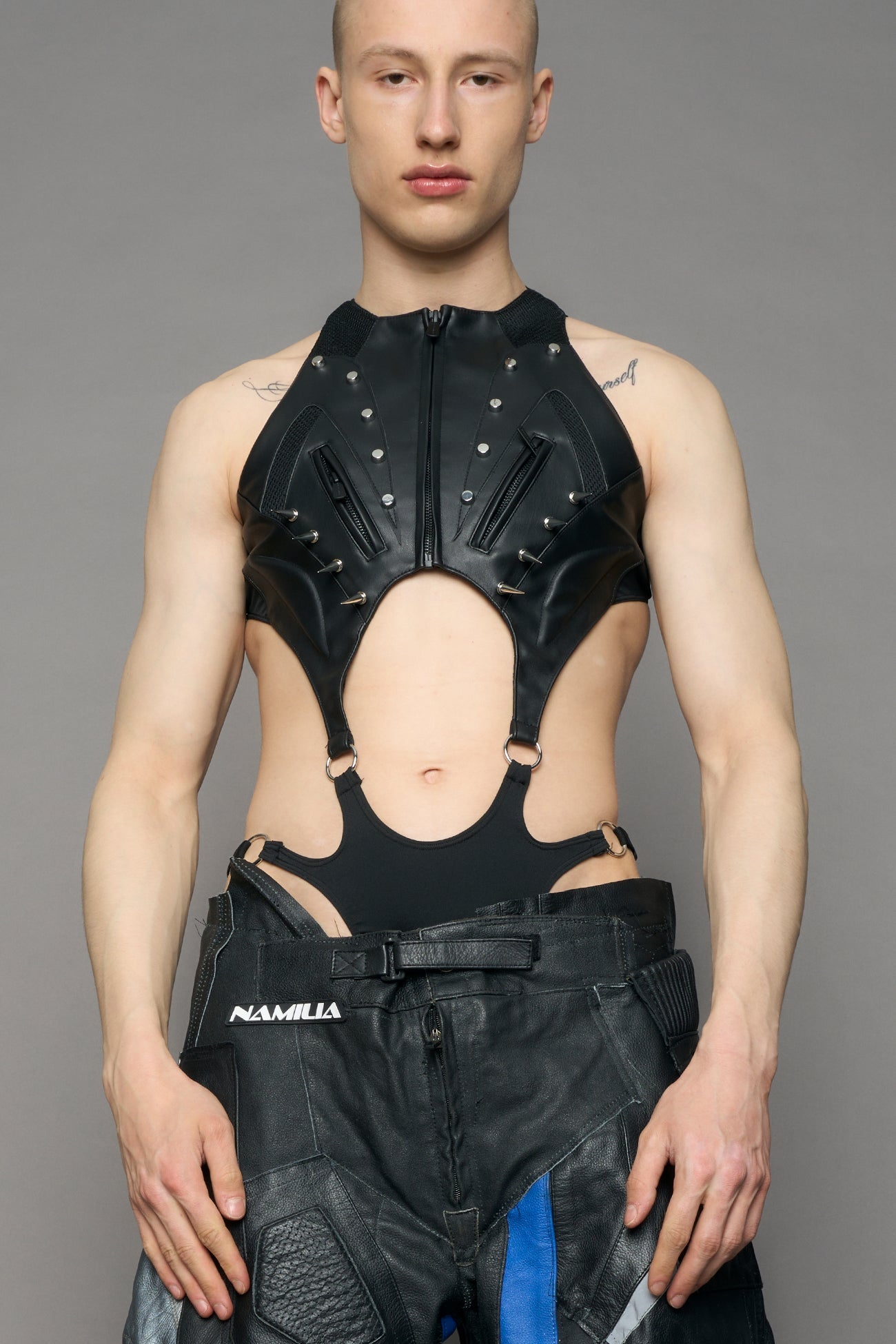 Person wearing a black bodysuit with cut-out design on a gray background