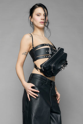 black vulva bum bag with adjustable strap and metal spike detailing worn as crossbody and shoulder bag studio ecommerce image