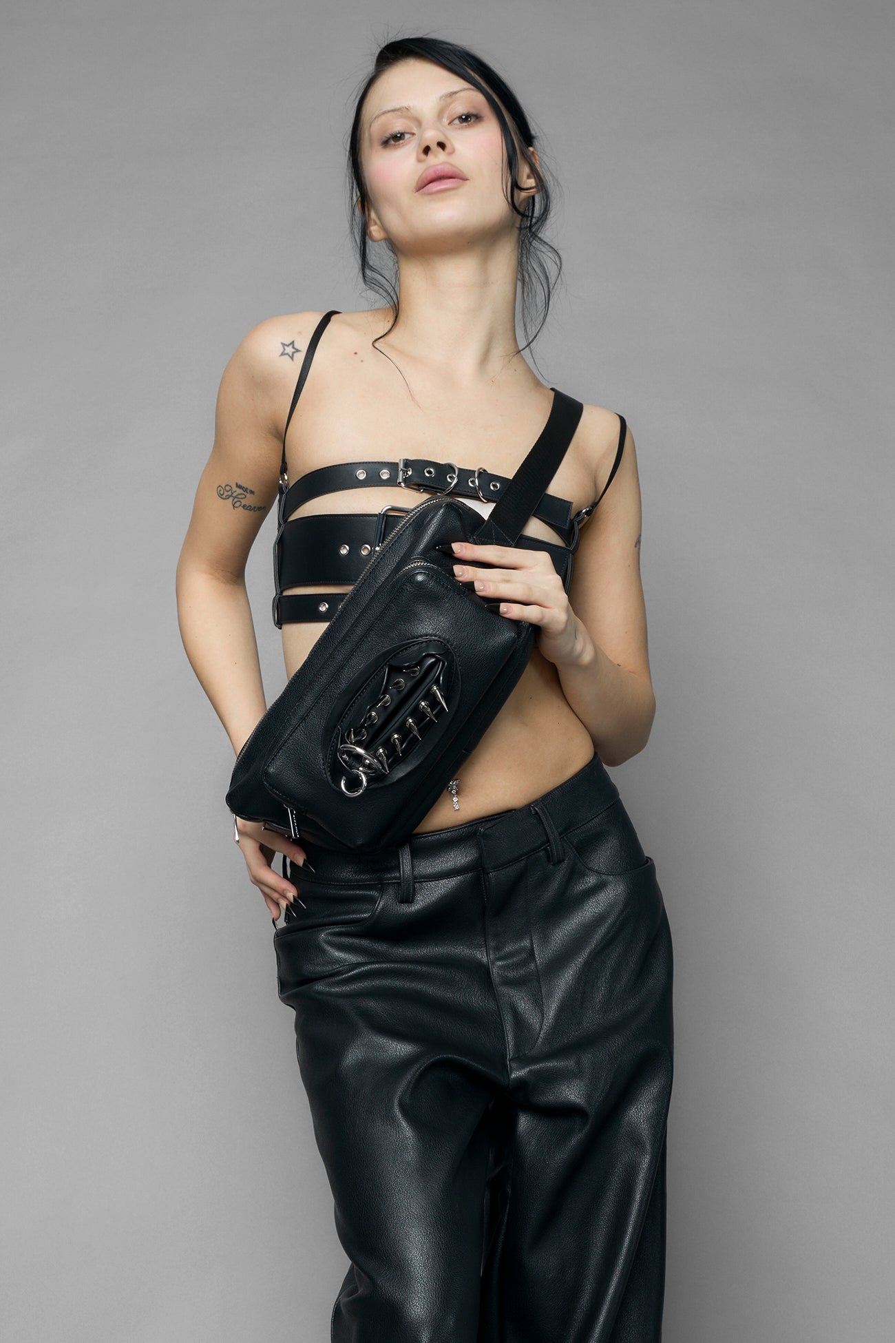 black vulva bum bag with adjustable strap and metal spike detailing worn as crossbody and shoulder bag studio ecommerce image