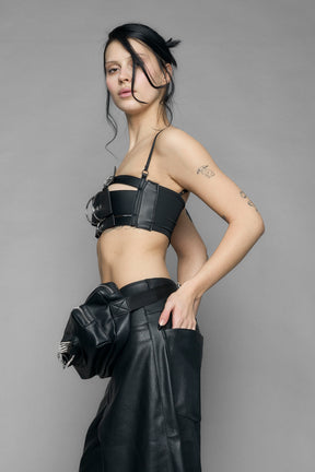 black vulva bum bag with adjustable strap and metal spike detailing worn as crossbody and shoulder bag studio ecommerce image