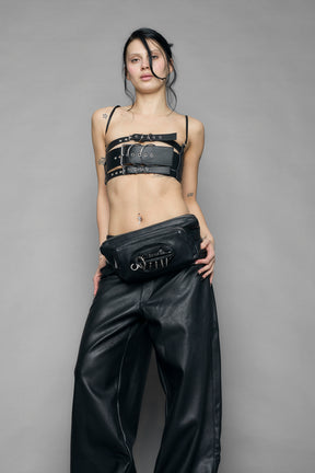 black vulva bum bag with adjustable strap and metal spike detailing worn as crossbody and shoulder bag studio ecommerce image