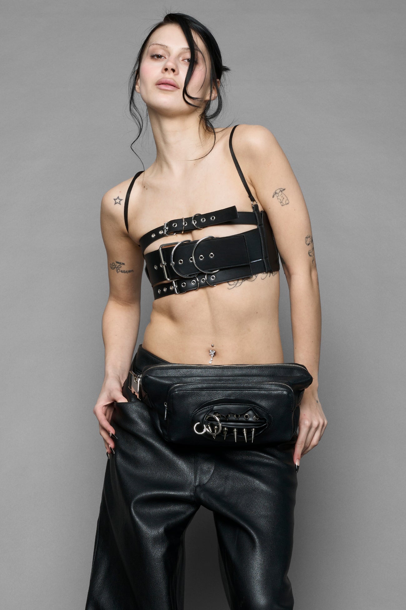 black vulva bum bag with adjustable strap and metal spike detailing worn as crossbody and shoulder bag studio ecommerce image