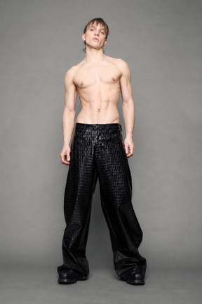 model wearing baggy suiting pants in black croc texture against a gray background
