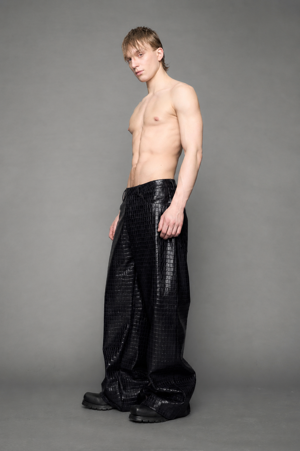 model wearing baggy suiting pants in black croc texture against a gray background