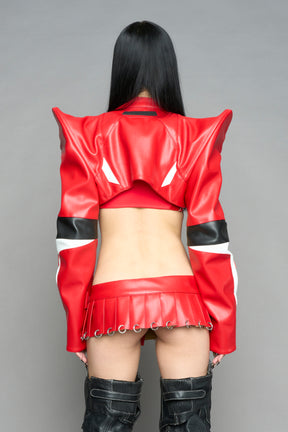 model wears the red Namilia Pleated Mini Skirt with ring piercing details on the hemline and velcro fold-over waistband closure.