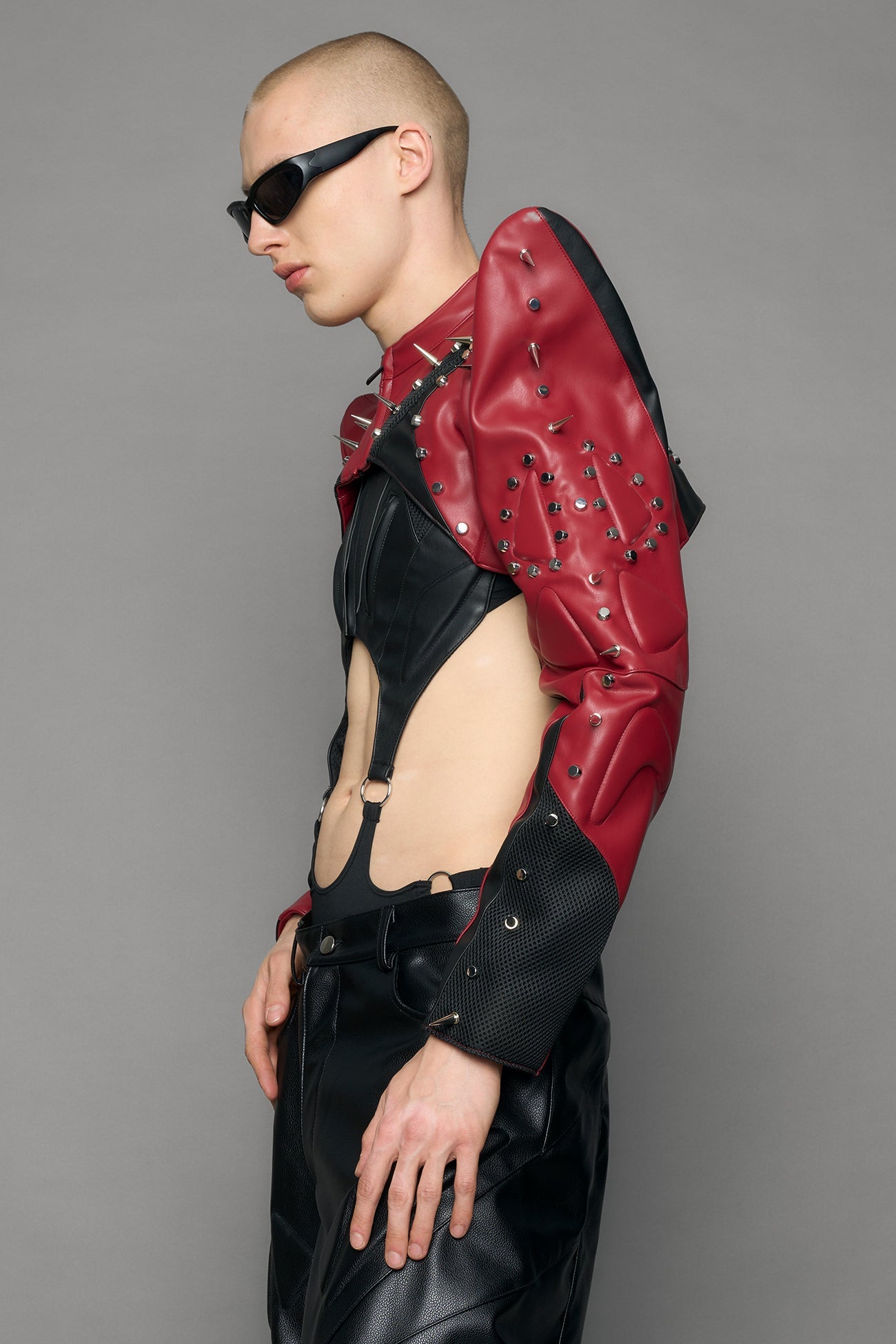 Model wearing a red studded leather choker jacket with cut-out design 
