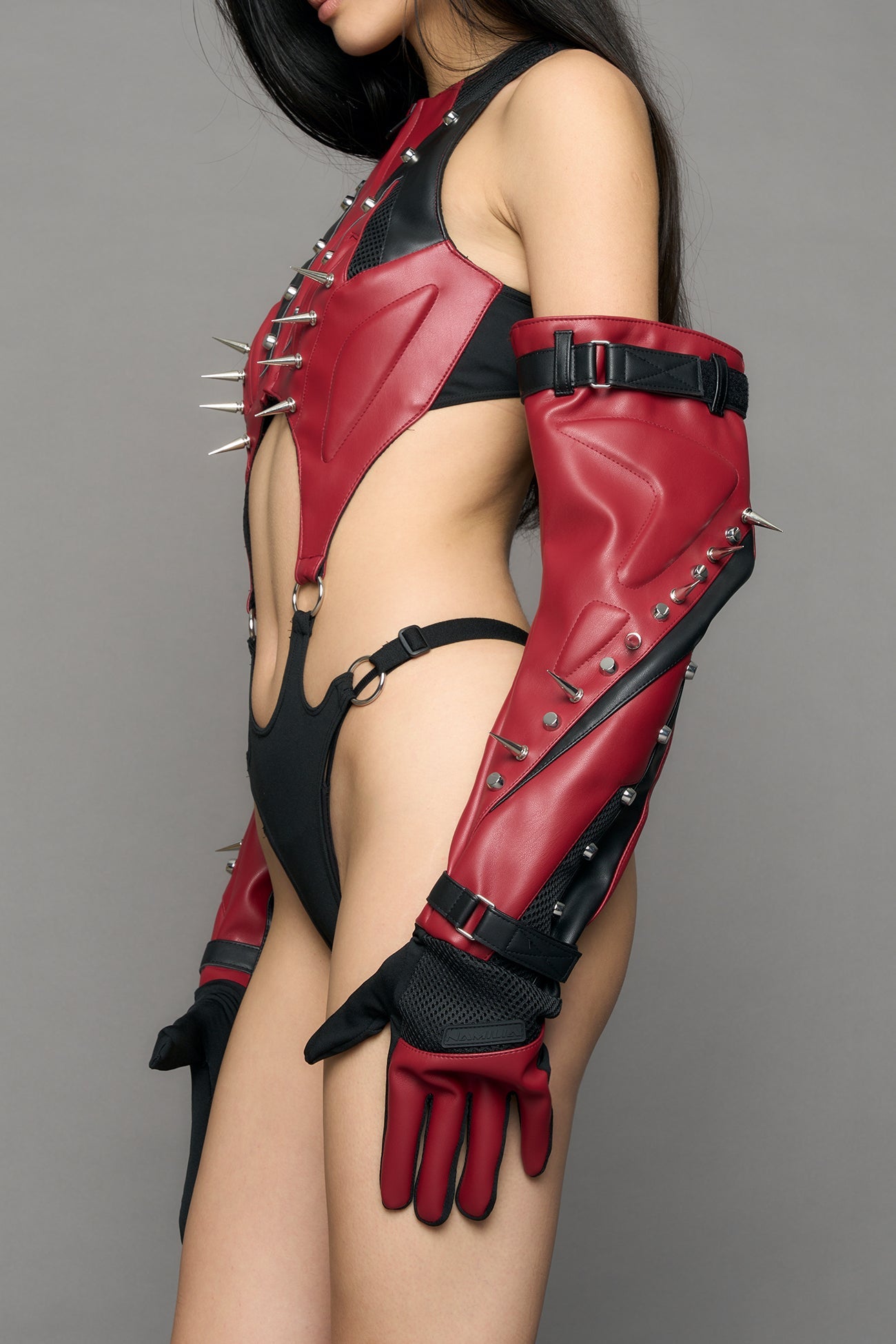 Model wearing a red studded leather gloves with silver and black details
