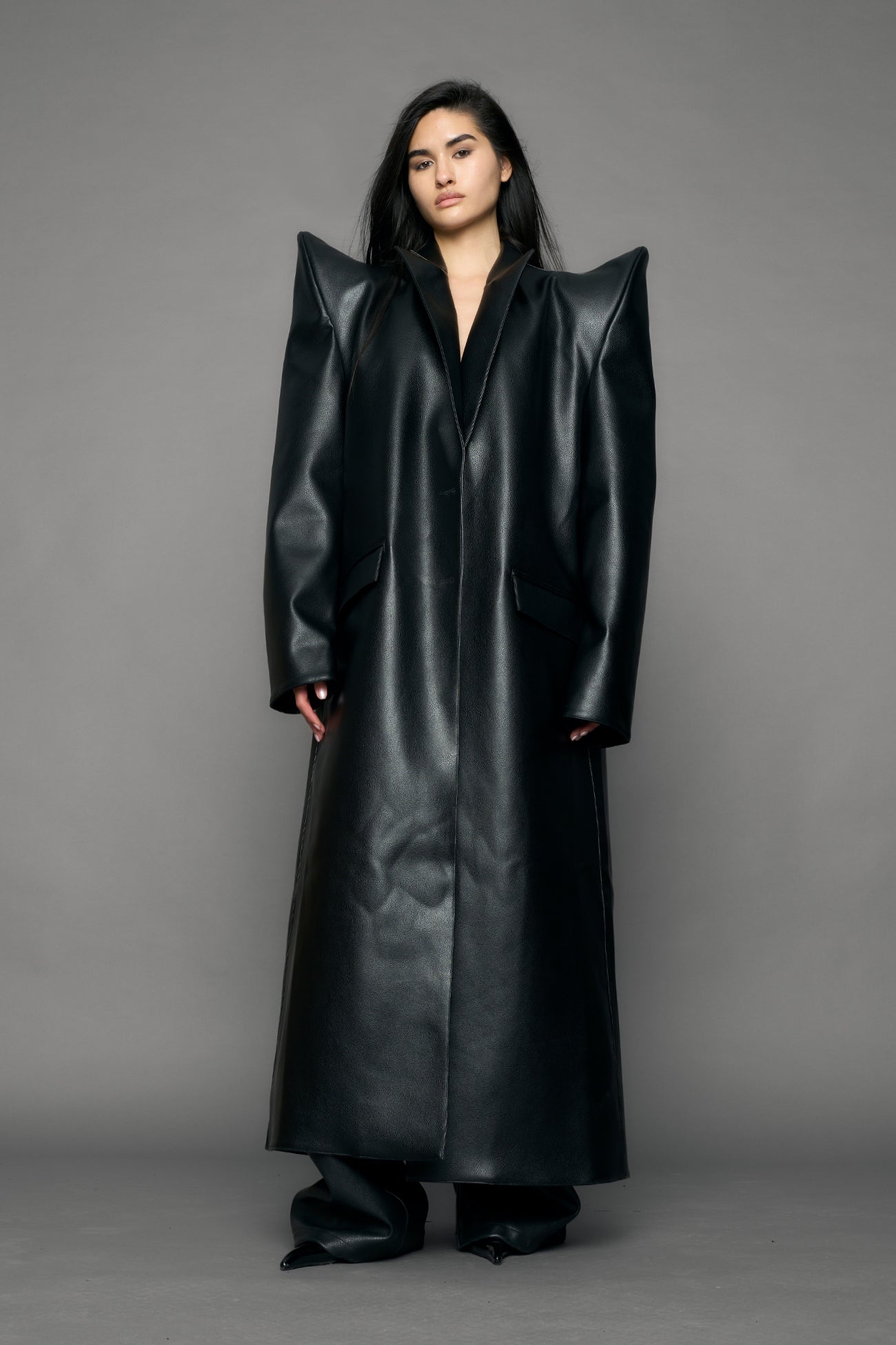 model wearing black pu leather coat with sharp shoulder design