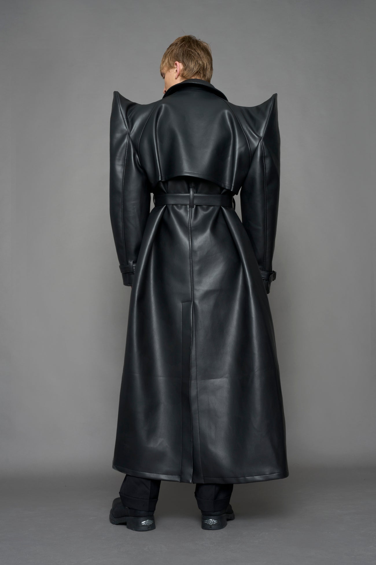 model wearing black vegan leather trench coat with sharp shoulder design