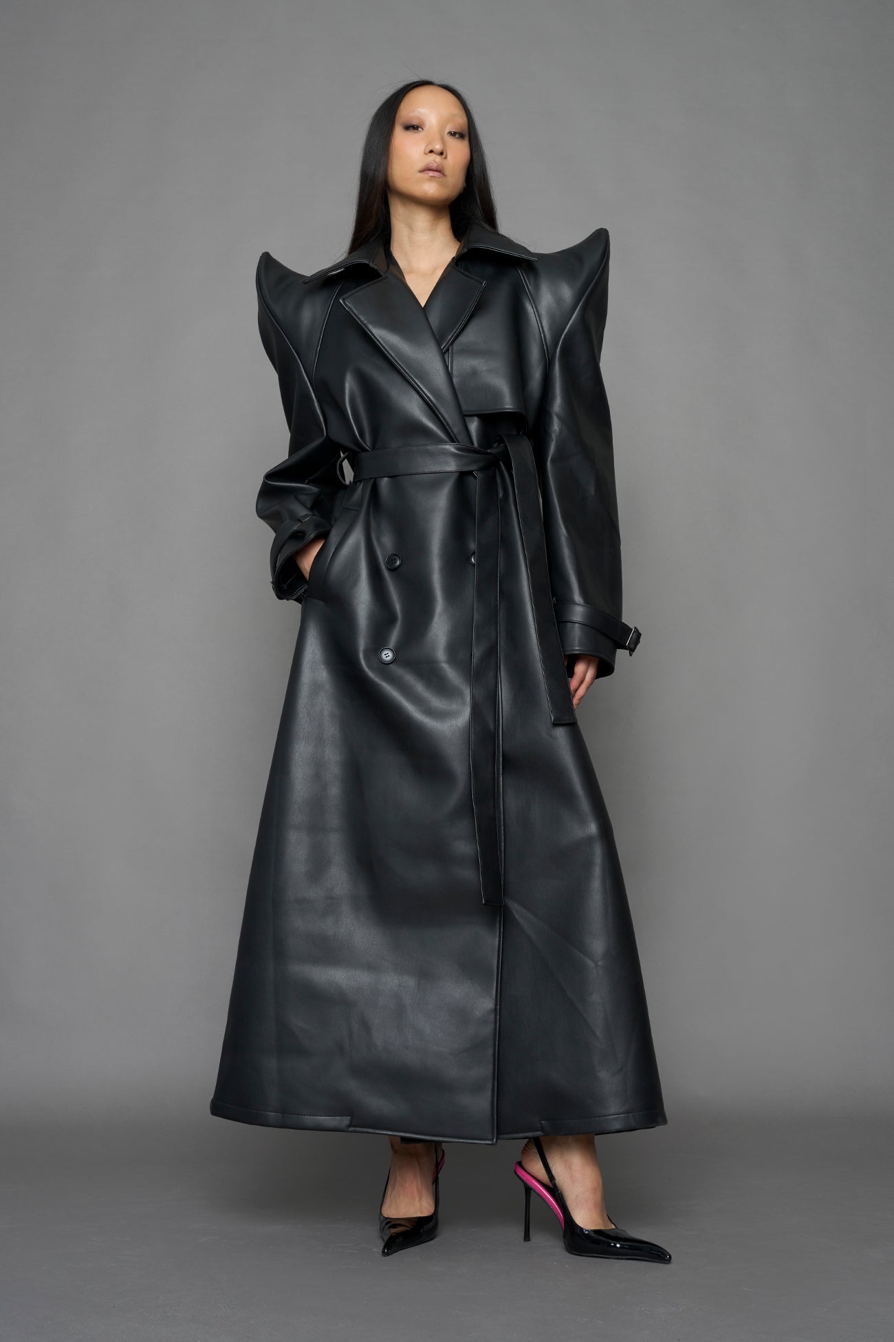 model wearing black vegan leather trench coat with sharp shoulder design