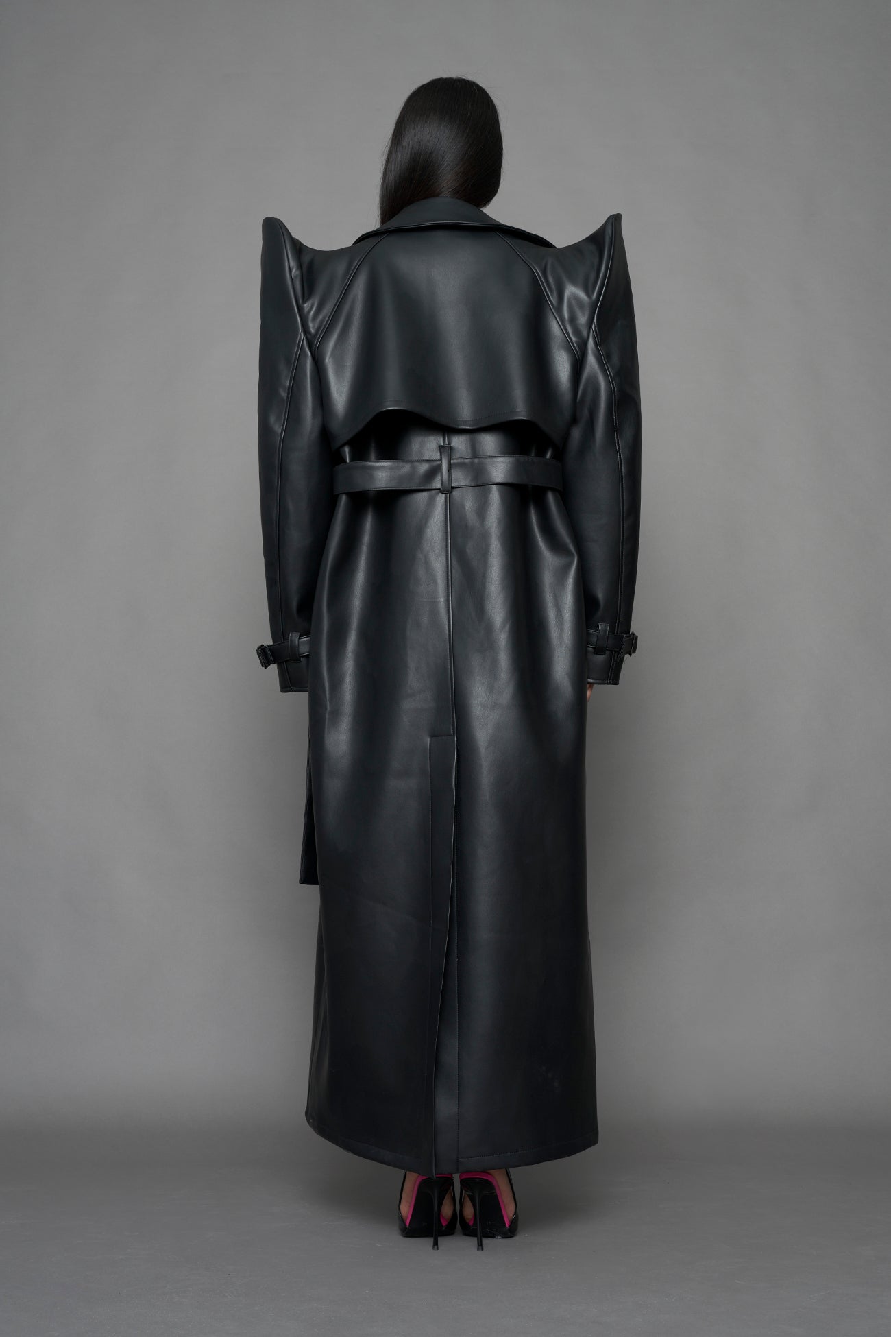 model wearing black vegan leather trench coat with sharp shoulder design