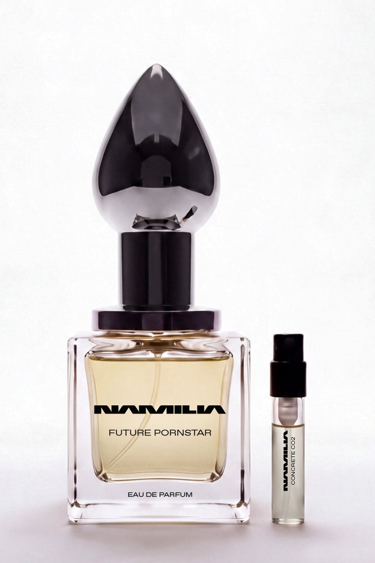 A bottle of Namila  Eau de Parfum with a large reflective plug-shaped cap with a tester on the side