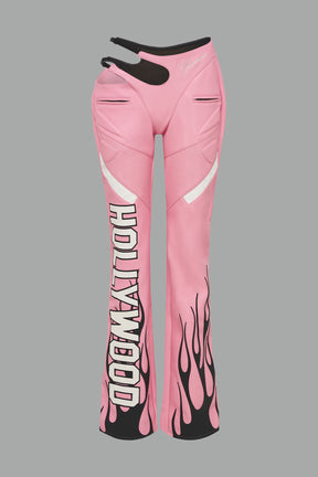 pink vegan leather flare trousers with motocross paneling, padded details, flame and cross stitching, slogan embroidery, and an asymmetric waistband with adjustable elastic thong straps.