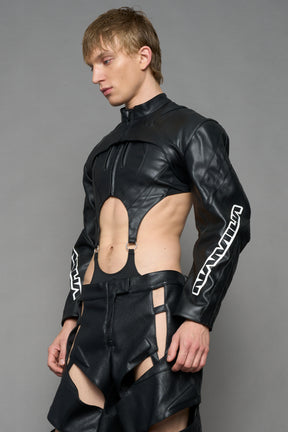 A male model wearing a black faux-leather long-sleeve top with a high collar and white graphic text on the sleeves
