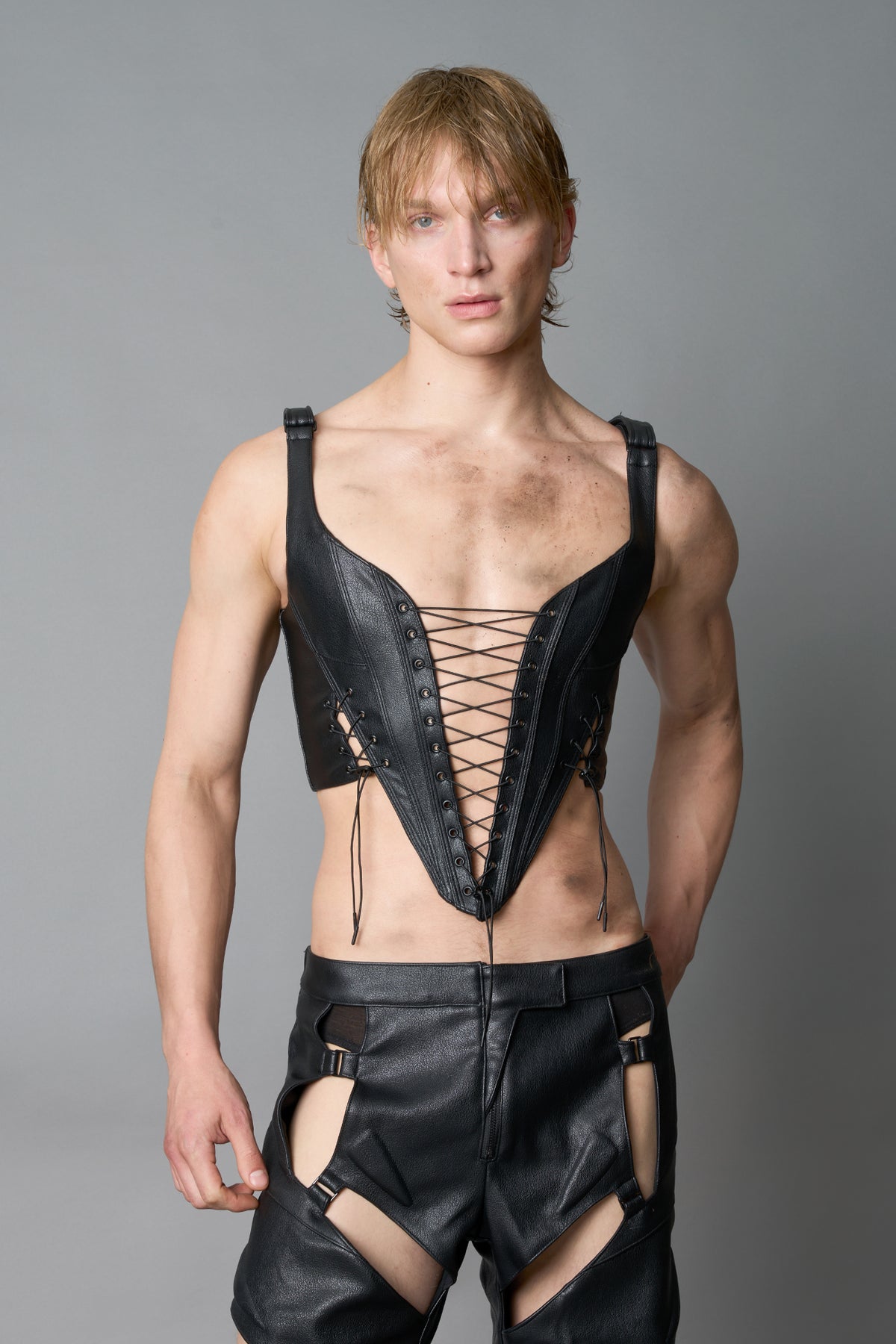 Model wearing black vegan leather XTC Corset by Namilia featuring extreme plunging neckline, front lace-up closure, and sculpted fit