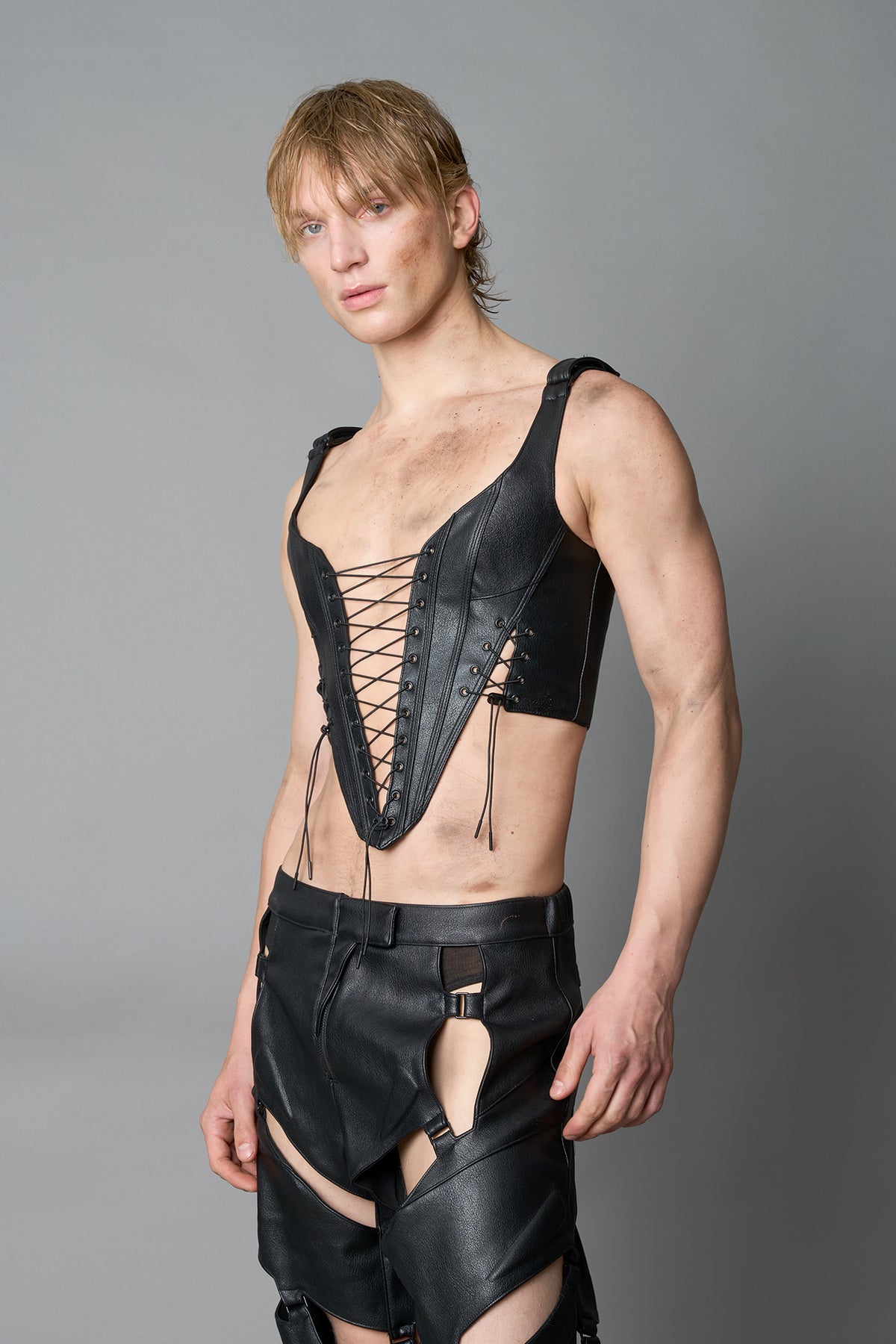 Model wearing black vegan leather XTC Corset by Namilia featuring extreme plunging neckline, front lace-up closure, and sculpted fit
