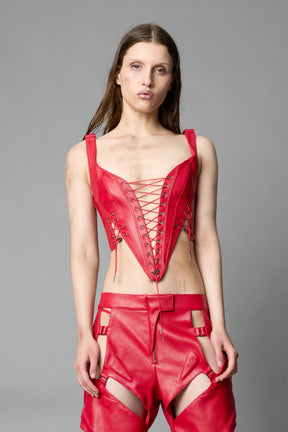 Model wearing red vegan leather XTC Corset by Namilia featuring extreme plunging neckline, front lace-up closure, and sculpted fit