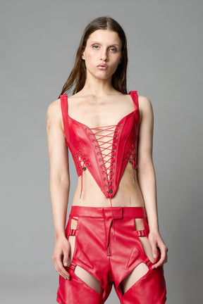 Model wearing red vegan leather XTC Corset by Namilia featuring extreme plunging neckline, front lace-up closure, and sculpted fit