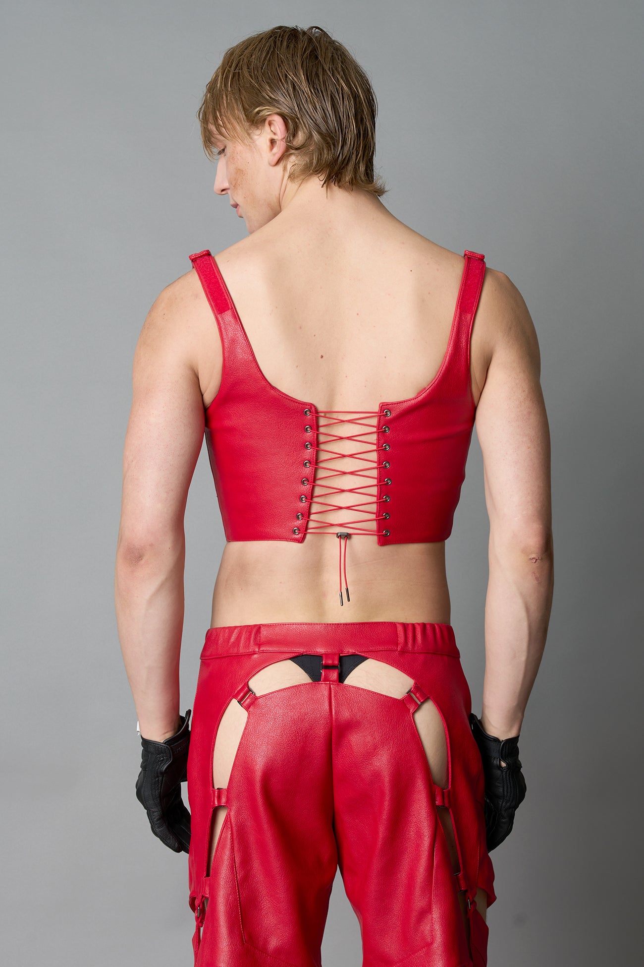 Model wearing red vegan leather XTC Corset by Namilia featuring extreme plunging neckline, front lace-up closure, and sculpted fit