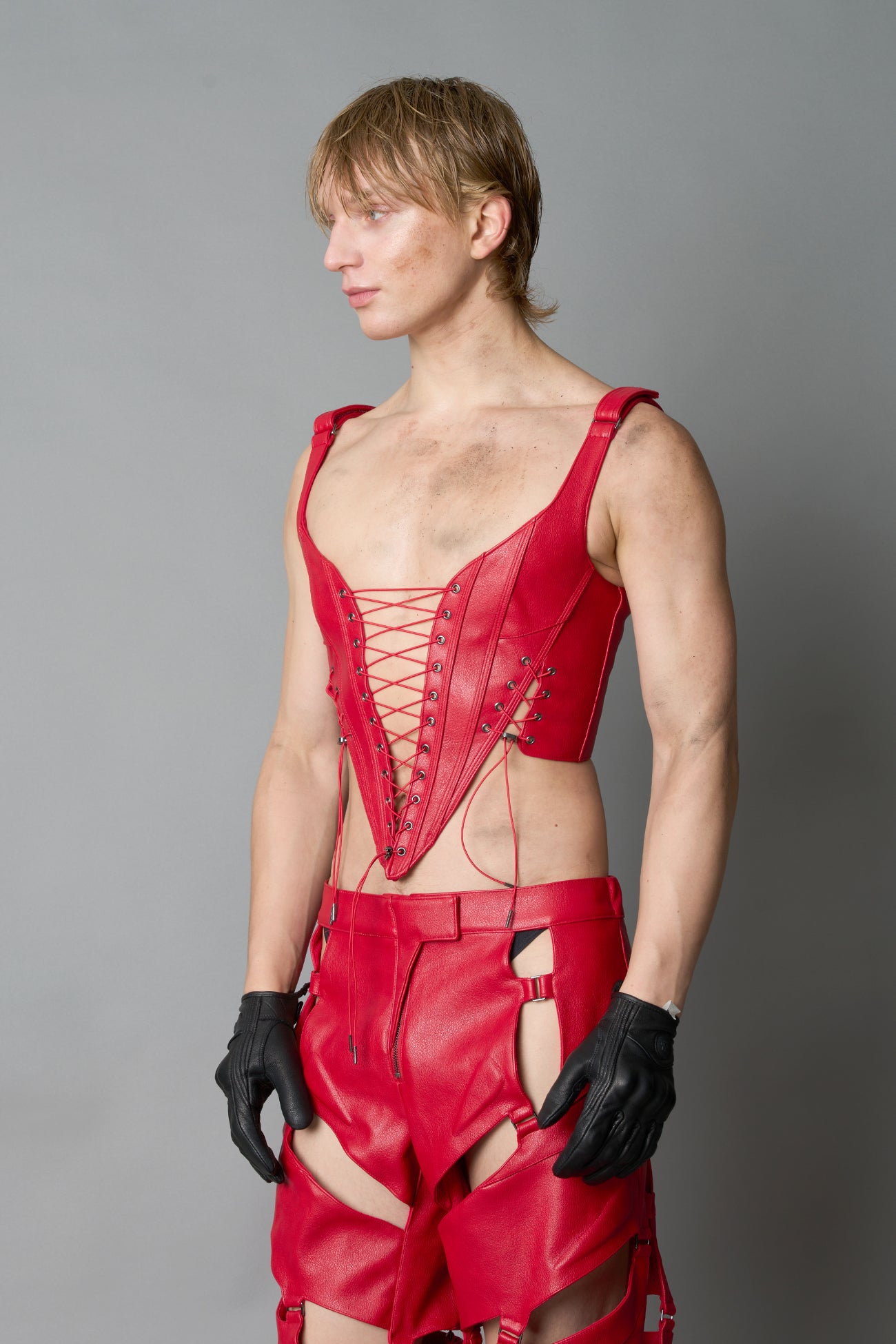 Model wearing red vegan leather XTC Corset by Namilia featuring extreme plunging neckline, front lace-up closure, and sculpted fit