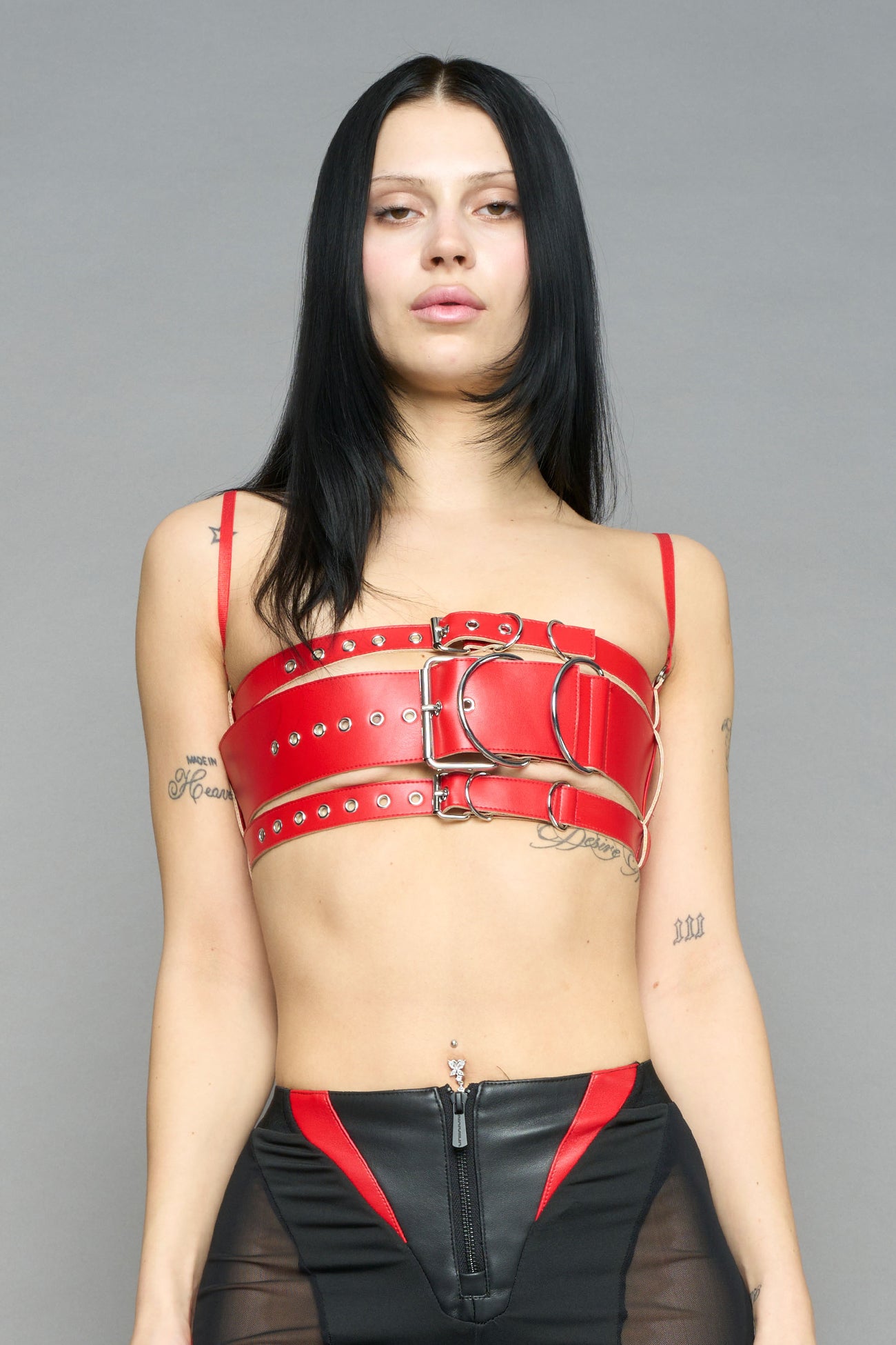 red vegan leather belt top with three adjustable grommet straps, oversized metal buckles, and circular hardware – edgy bondage-inspired crop top for festival or clubwear.
