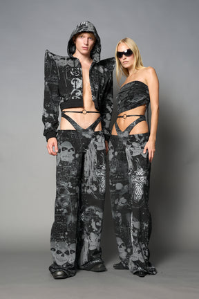Model wearing low-rise black print wide-leg pants featuring a V-shaped waistband and detachable thong strap detail.