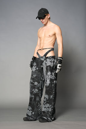 Model wearing low-rise black print wide-leg pants featuring a V-shaped waistband and detachable thong strap detail.
