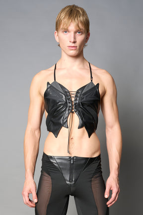 model wears black vegan leather butterfly crop top with lace-up front, halter straps, and mesh accents – edgy Y2K-inspired statement piece for festivals or streetwear.