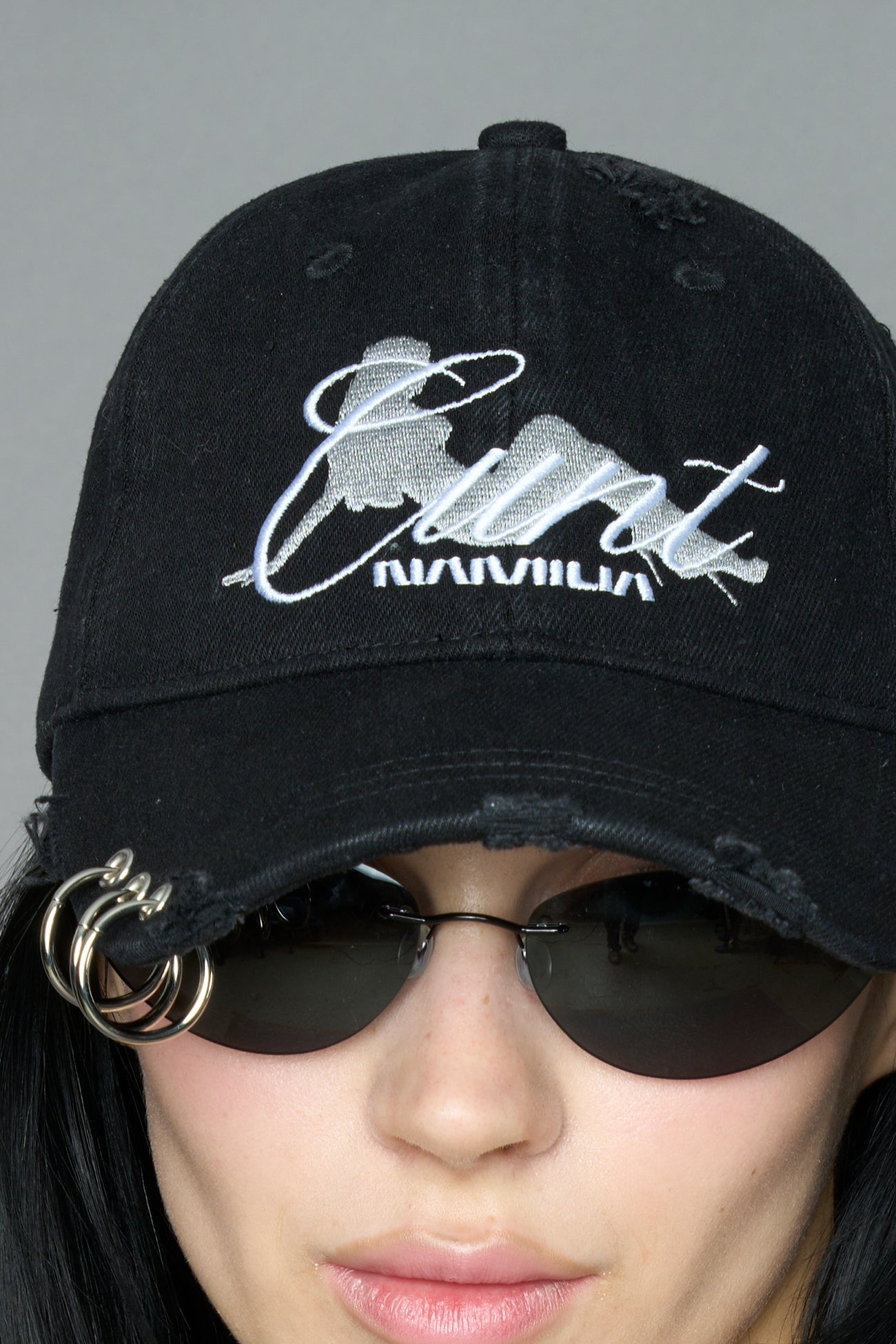 model wearing grey slogan embroidered rtrucker cap with silver ring details