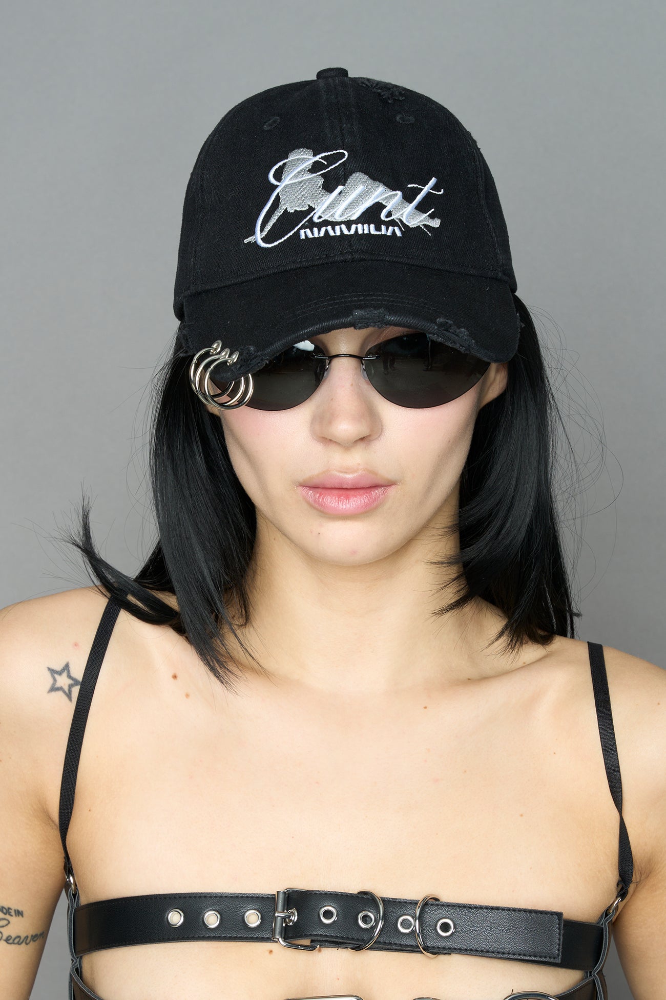 model wearing grey slogan embroidered rtrucker cap with silver ring details
