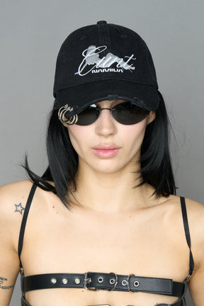 model wearing grey slogan embroidered rtrucker cap with silver ring details
