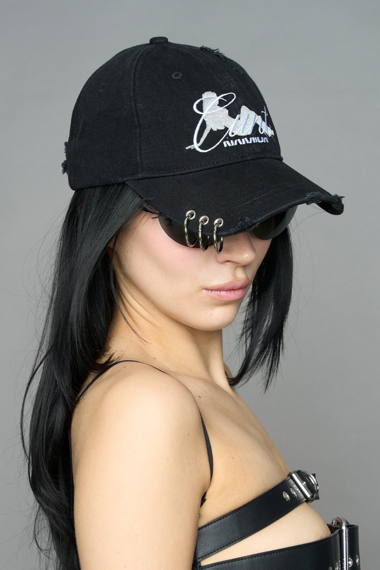 model wearing grey slogan embroidered rtrucker cap with silver ring details