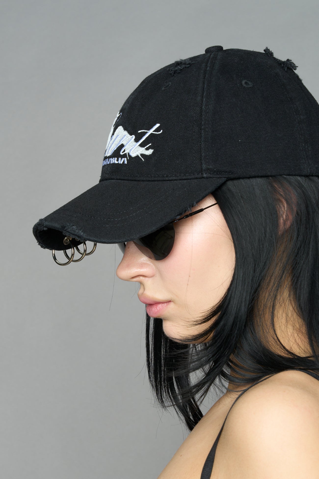 model wearing grey slogan embroidered rtrucker cap with silver ring details