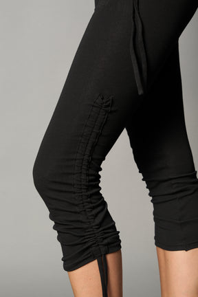 Model wearing black capri pants with ruched sides and matching off-shoulder crop top