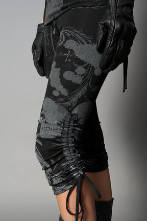 Model wearing black print capri pants with ruched sides and matching off-shoulder crop top