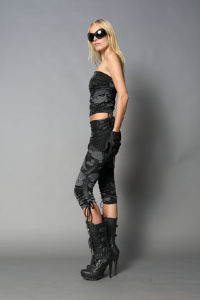 Model wearing black print capri pants with ruched sides and matching off-shoulder crop top