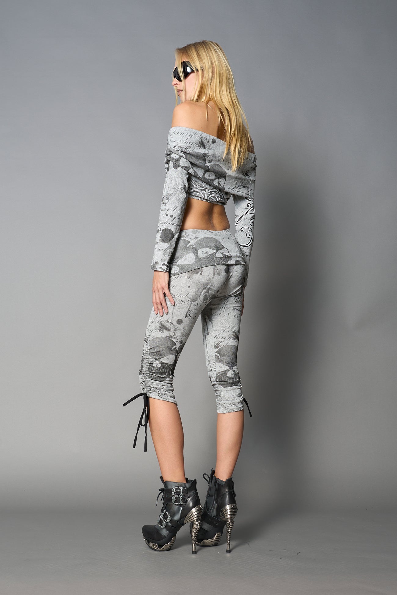 Model wearing grey print capri pants with ruched sides and matching off-shoulder crop top