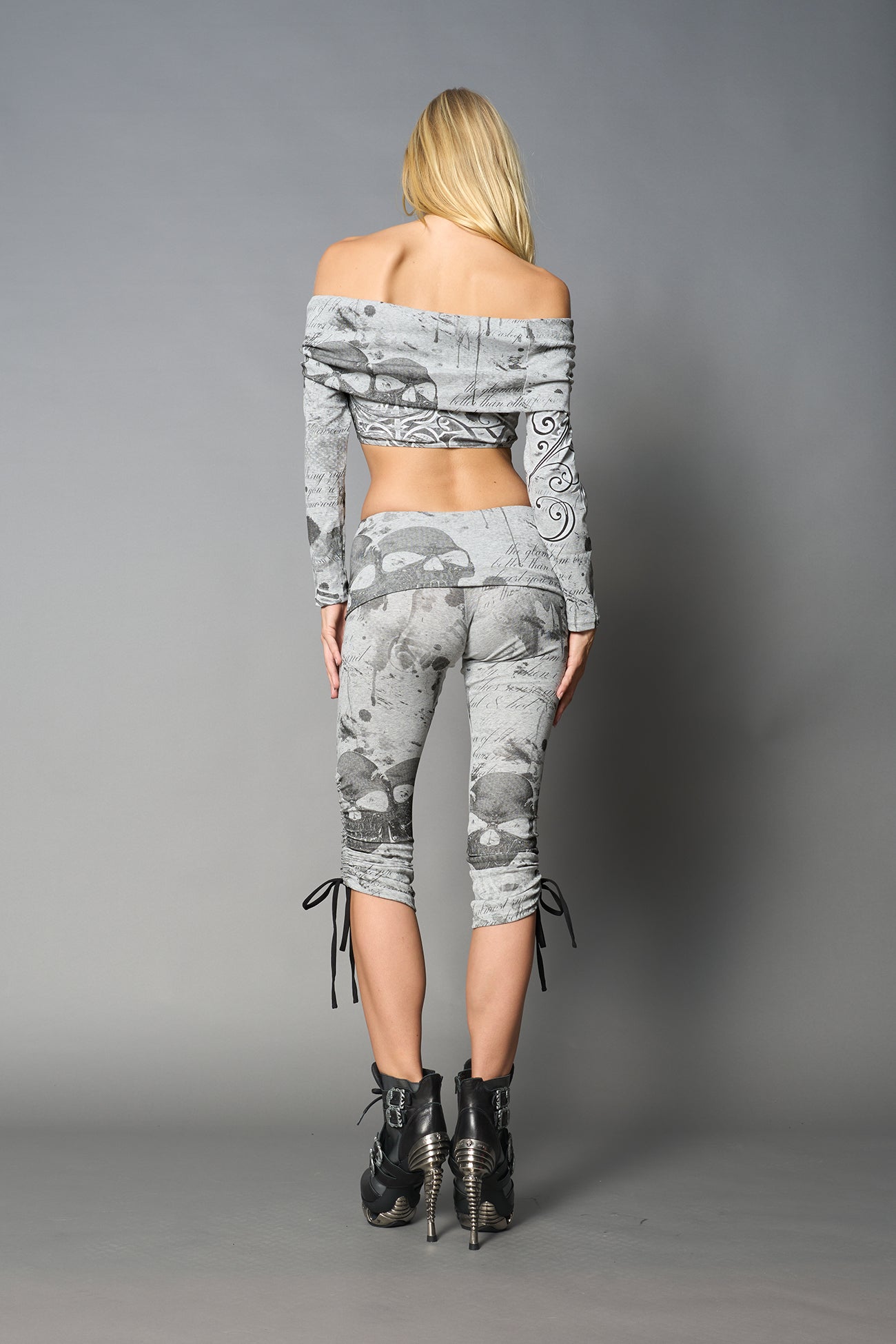 Model wearing grey print capri pants with ruched sides and matching off-shoulder crop top
