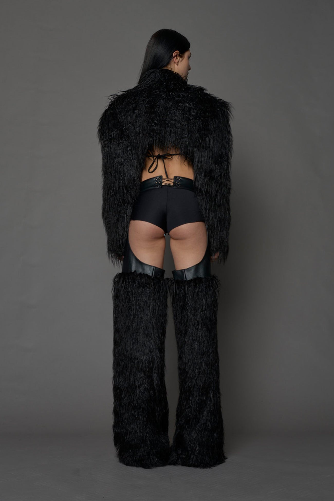 model wearing black vegan leather and faux fur chaps