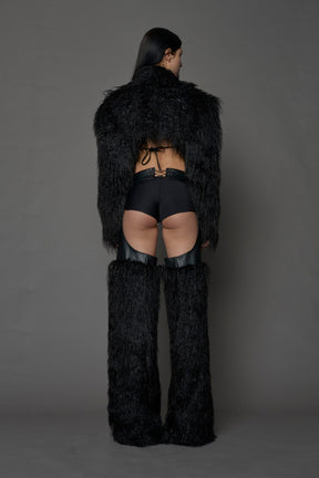 model wearing black vegan leather and faux fur chaps