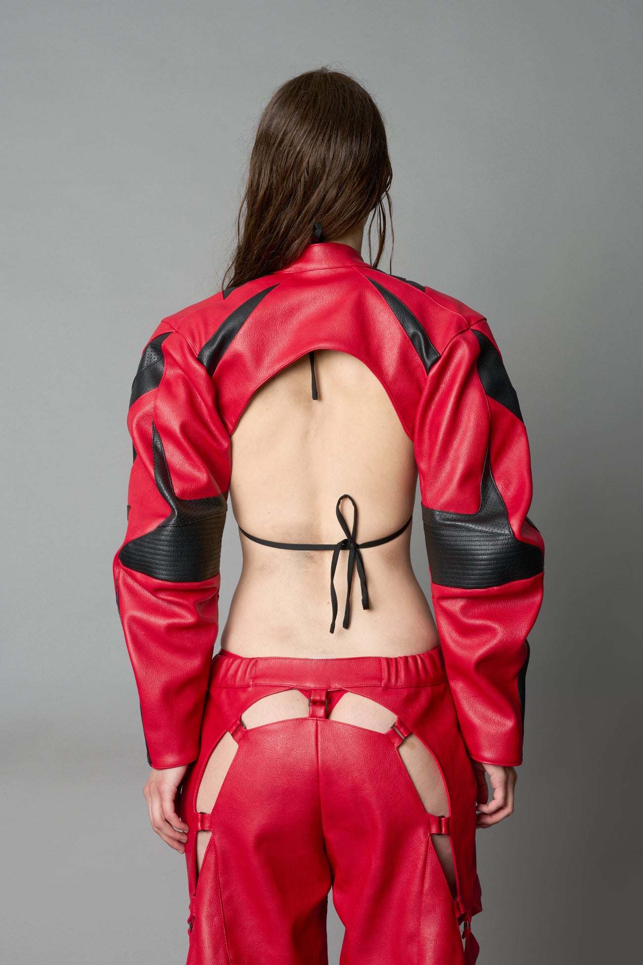Model wearing a red vegan leather cropped jacket with a high choker collar and zipper front
