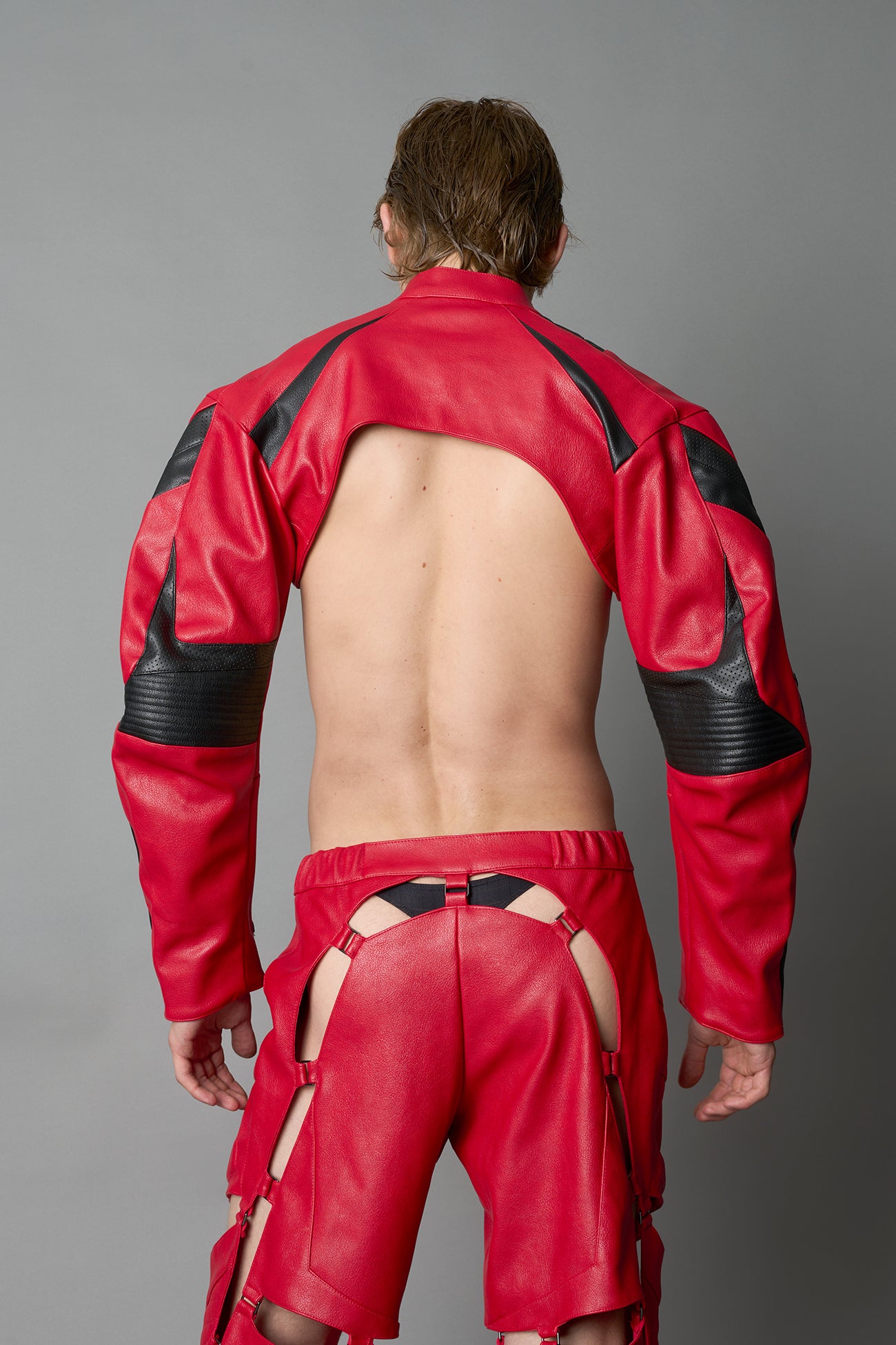 Model wearing a red vegan leather cropped jacket with a high choker collar and zipper front