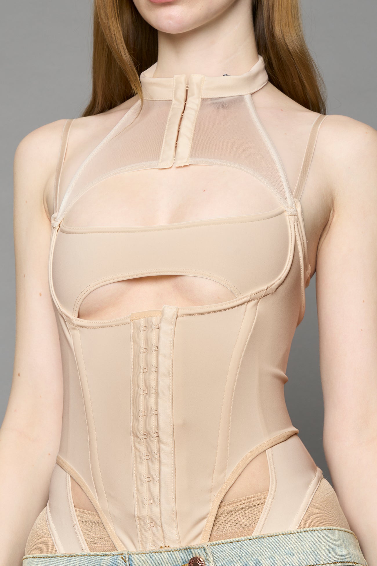 beige contour body by NAMILIA featuring a sculpted fit, corset-style waist with hook-and-eye closure, and high neckline. Statement bodywear.