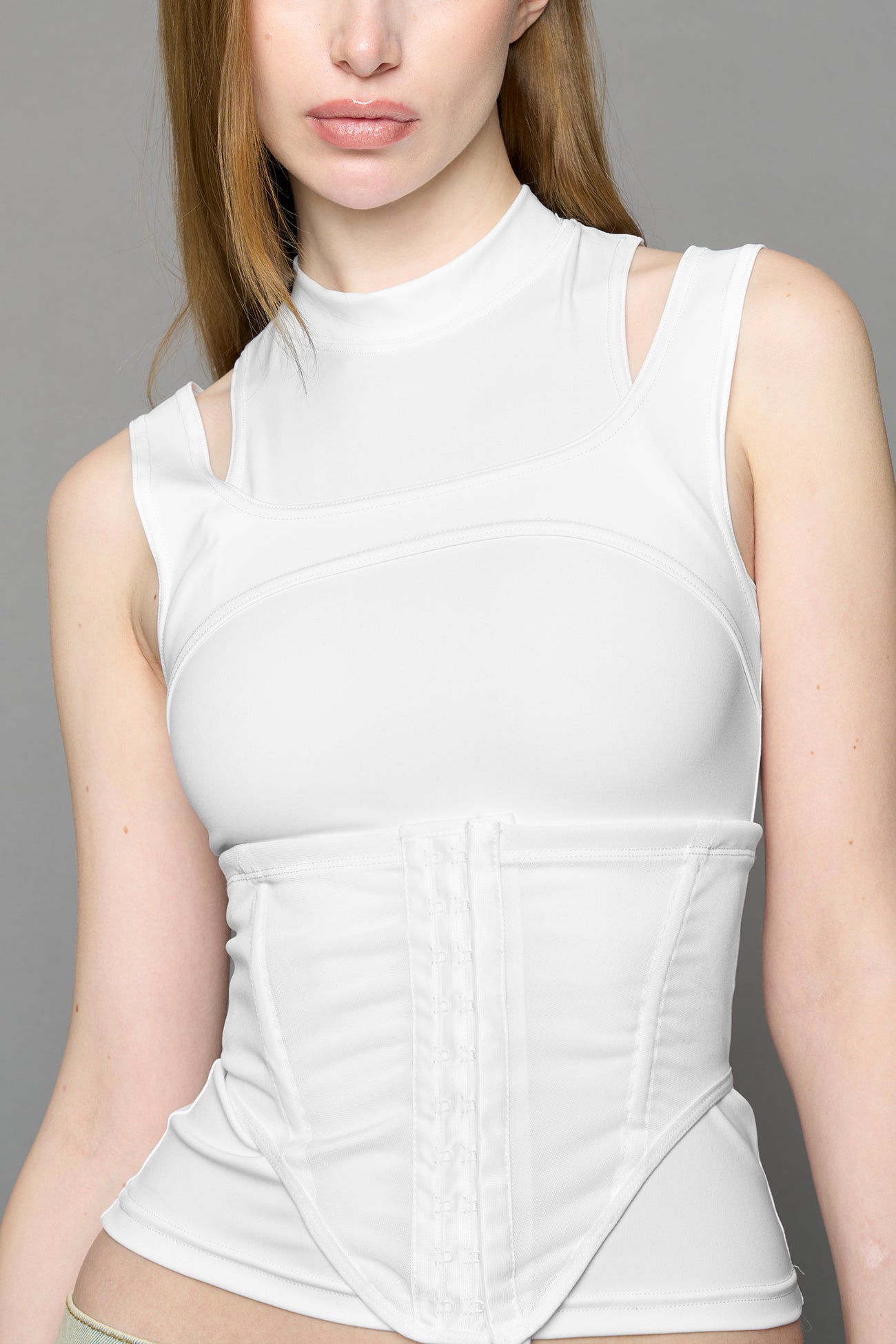 white contour top by NAMILIA featuring a sculpted fit, corset-style waist with hook-and-eye closure, and high neckline. Statement shaping top.