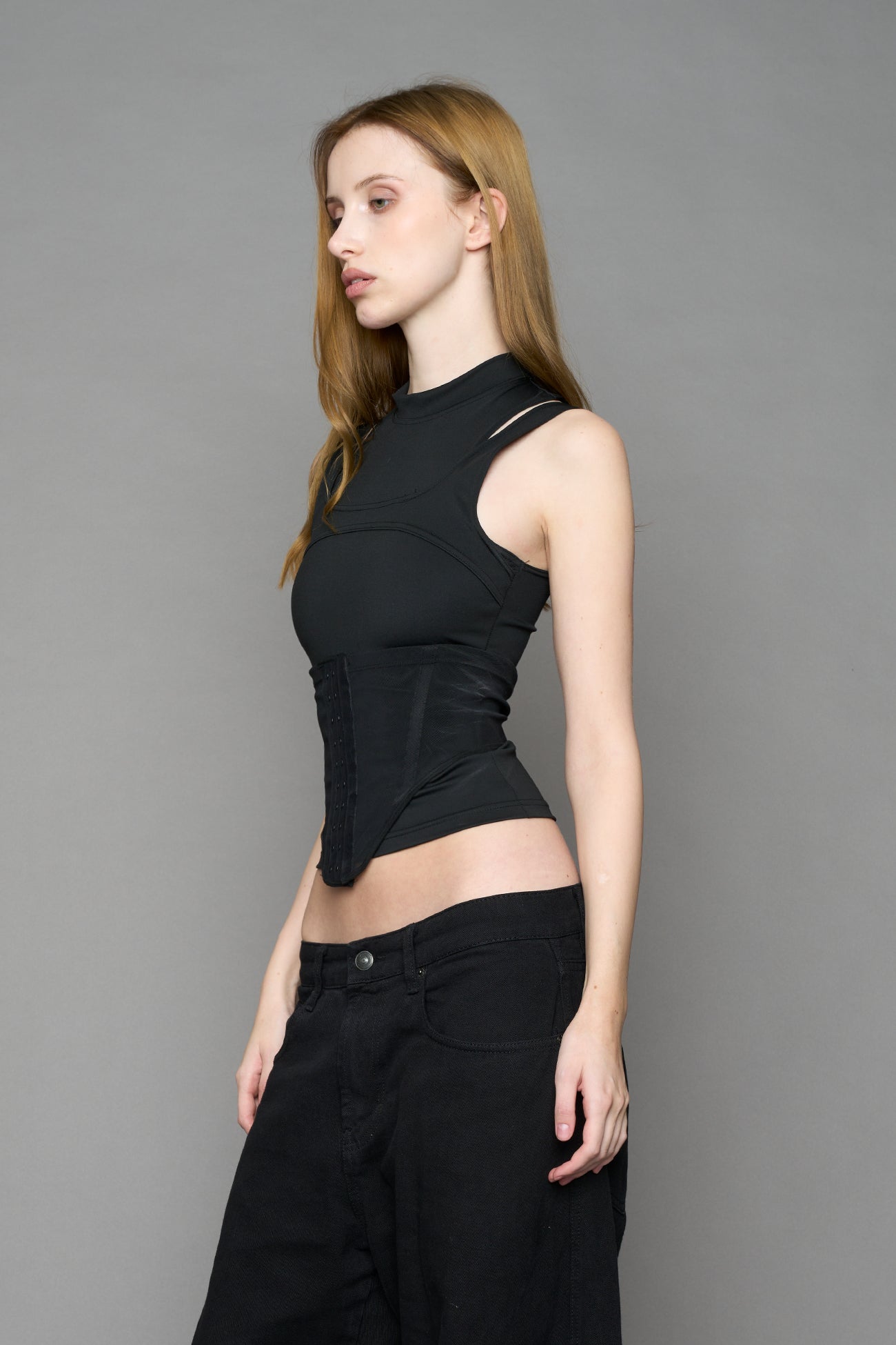 Black contour top by NAMILIA featuring a sculpted fit, corset-style waist with hook-and-eye closure, and high neckline. Statement shaping top.