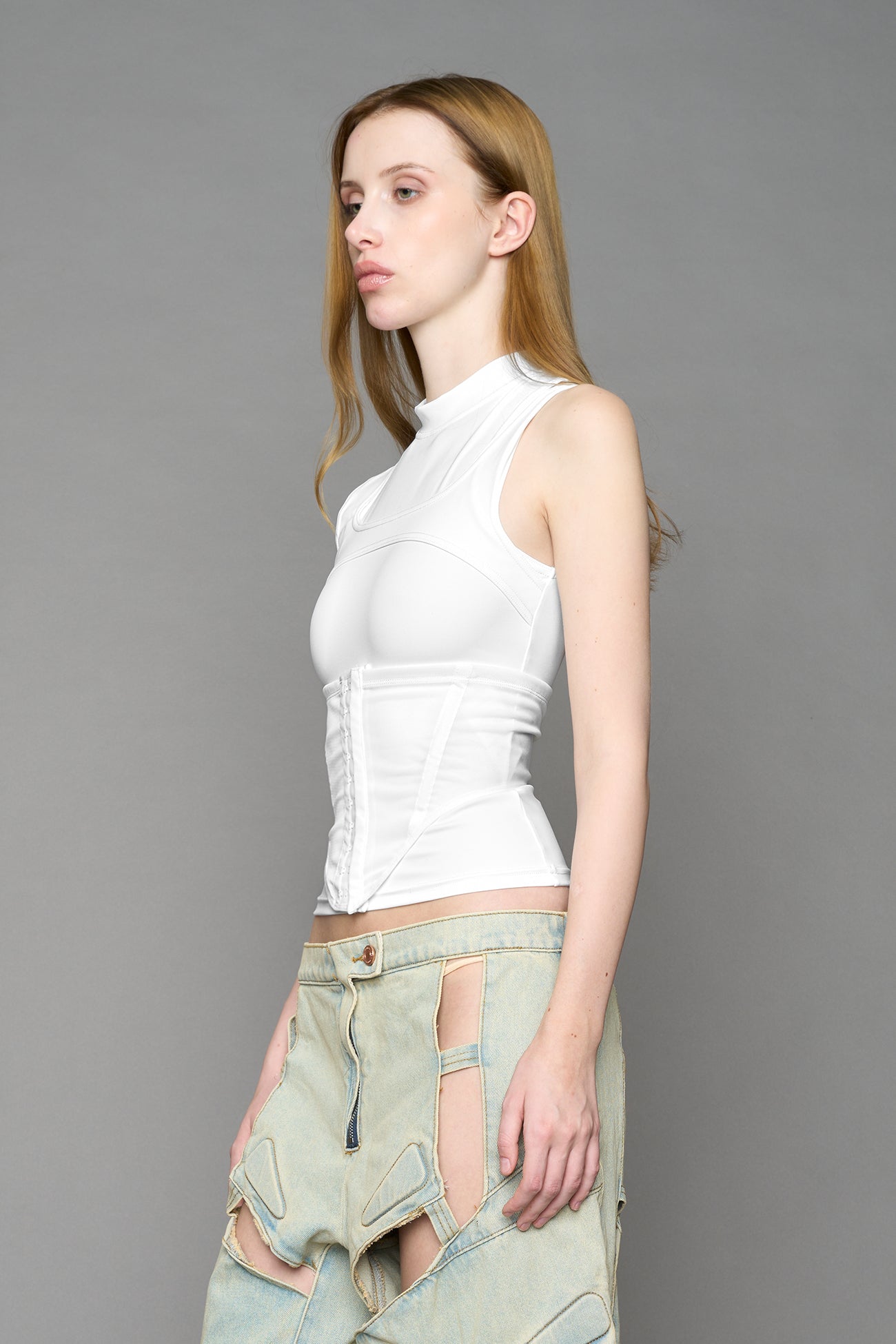 white contour top by NAMILIA featuring a sculpted fit, corset-style waist with hook-and-eye closure, and high neckline. Statement shaping top.