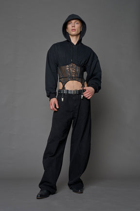 male model wearing a lingerie-inspired black hoodie with a lace corset 