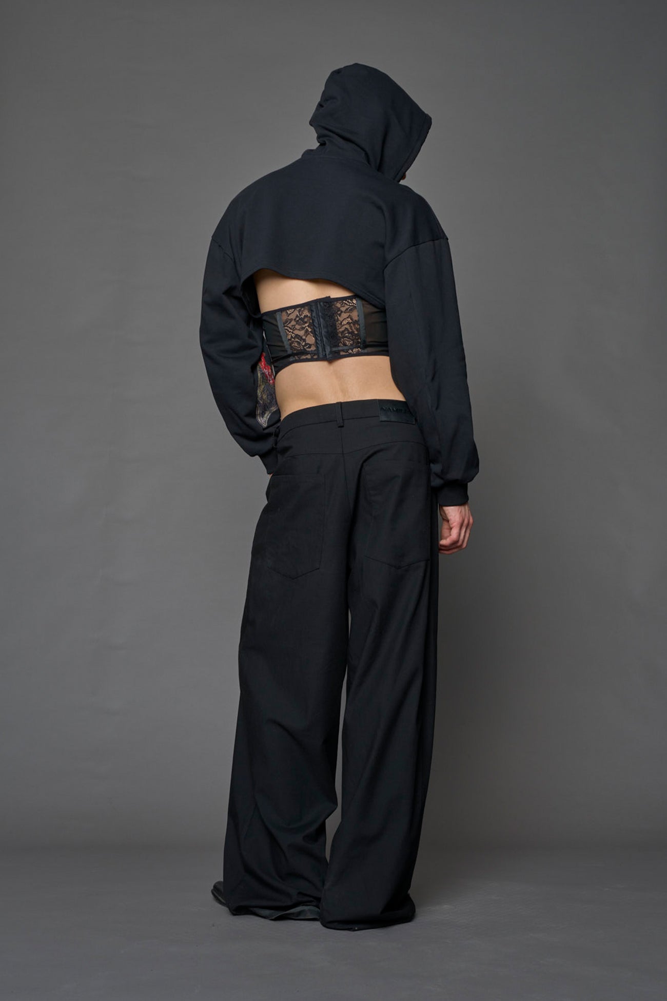 male model wearing a lingerie-inspired black hoodie with a lace corset 